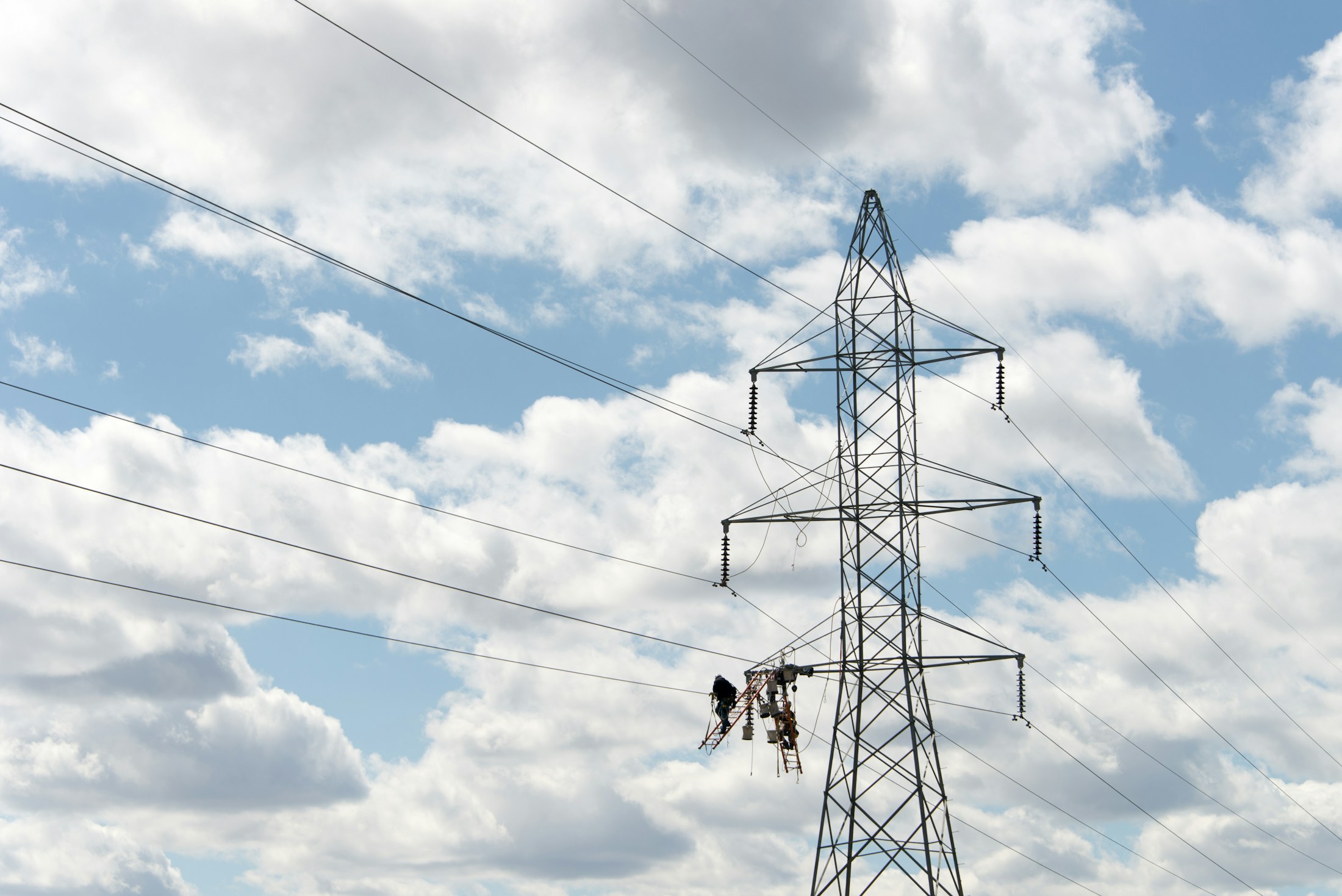 A high-voltage transmission tower and lines being maintained by engineers